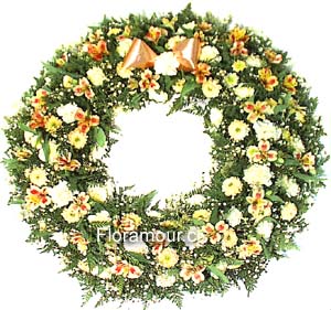 Arreglo floral circular (corona) apropiado para funeral, con un hoyo central, confeccionado con flores mixtas en tonos pasteles. 